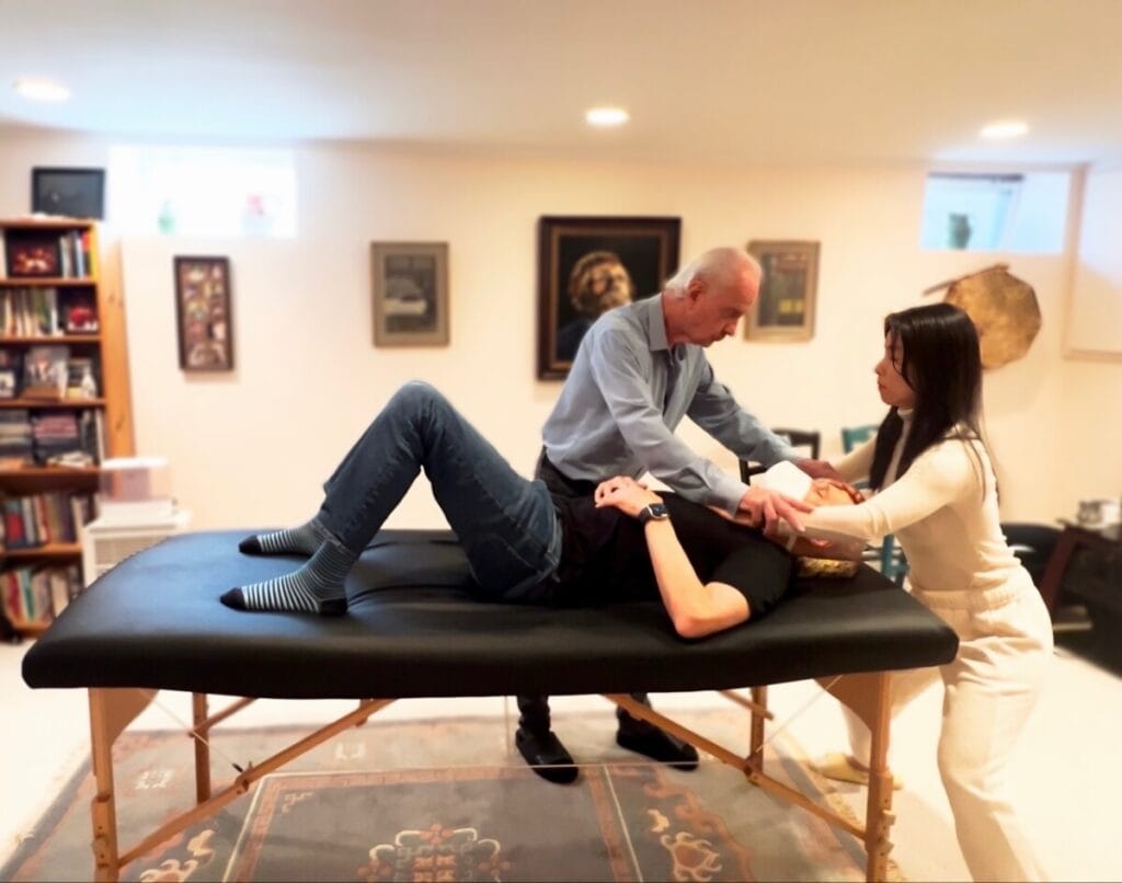 	Tommy Thompson teaching a trainee hands-on tablework in the Alexander Technique, guiding movement identity through touch.