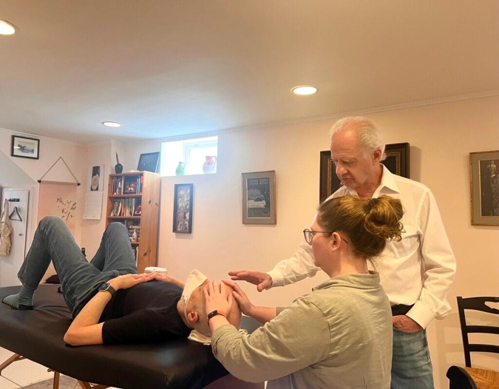 Trainee practicing Alexander Technique hands-on work under Tommy Thompson’s supervision during a structured class focused on dialog.