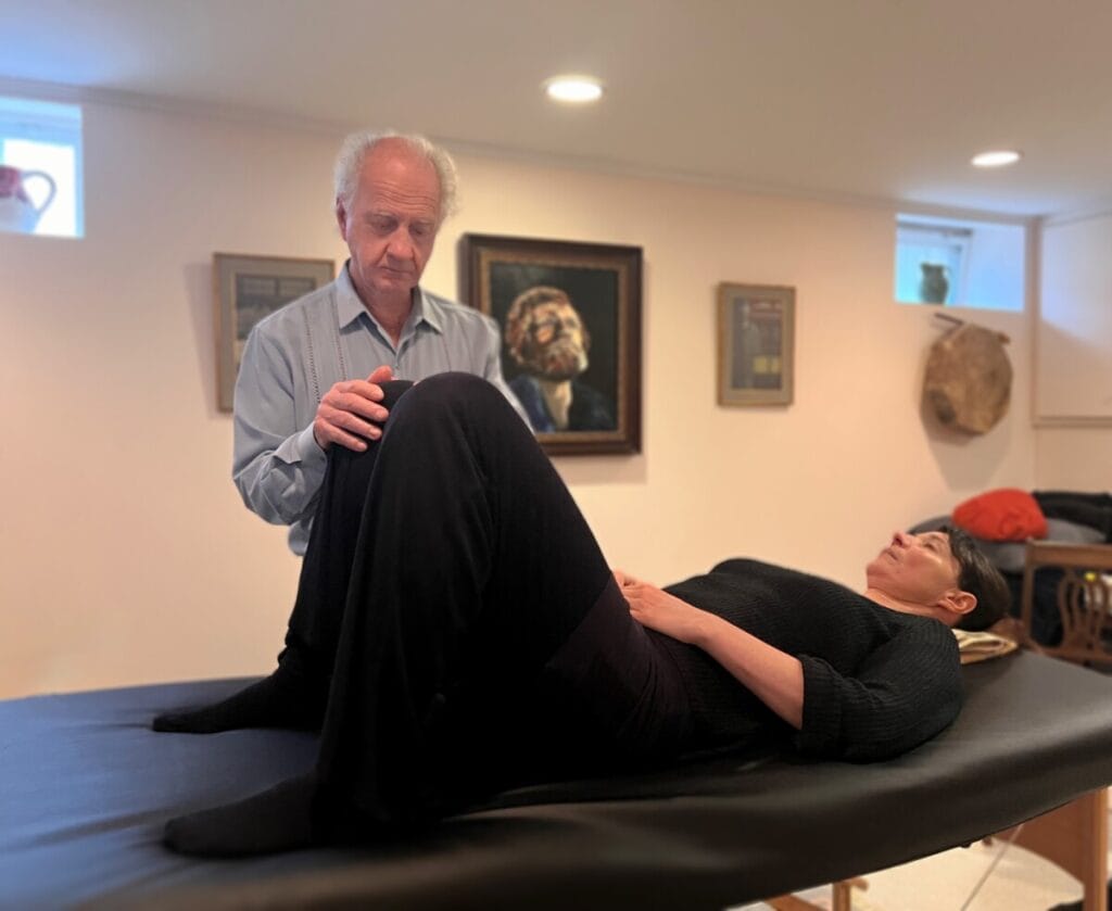 Tommy Thompson guiding a trainee through embodied awareness using the Alexander Technique on a table