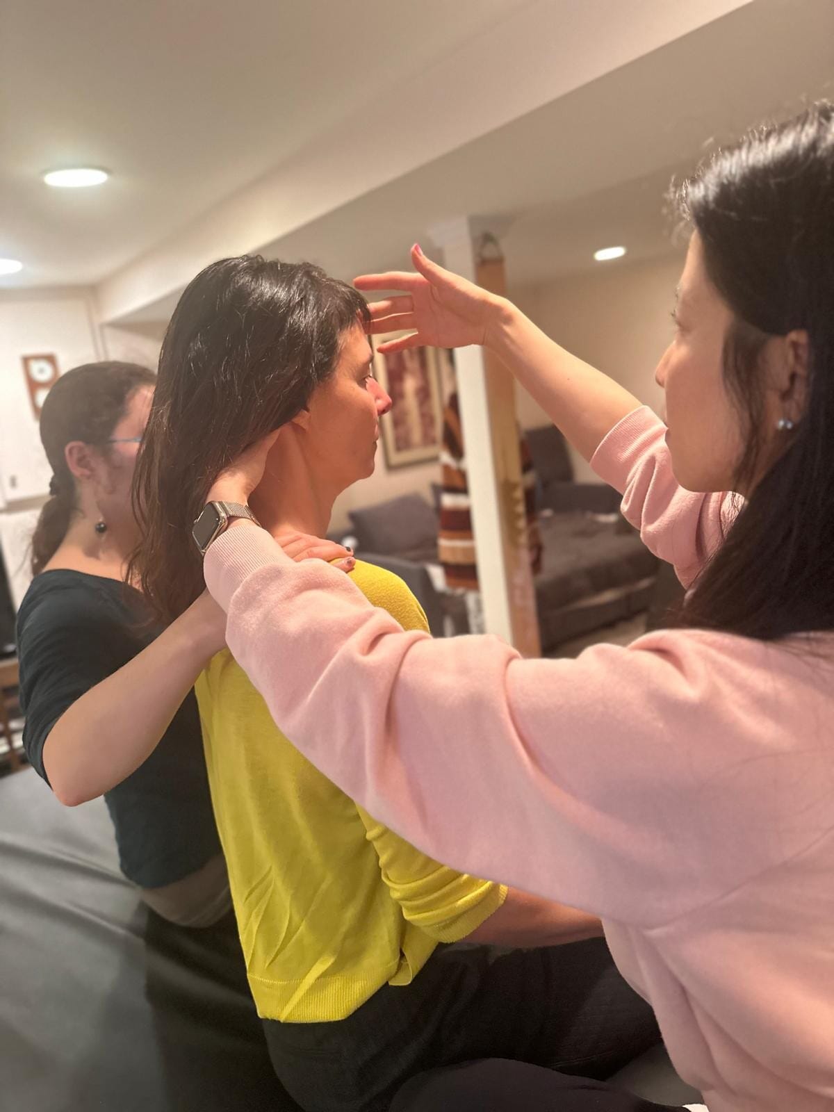 Two trainees support a fellow participant’s head and neck in a Tommy Thompson Alexander Technique class, exploring the application of inhibition in movement.