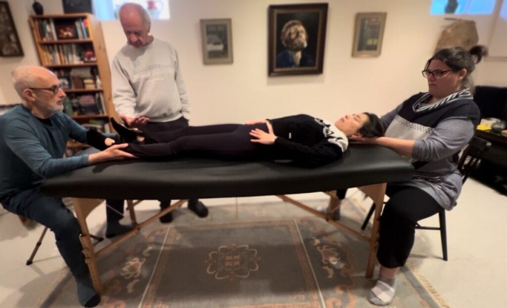 Two trainees engaged in Alexander Technique table work under Tommy Thompson’s guidance, exploring Triadic Resonance and discovering natural support through presence and alignment.
