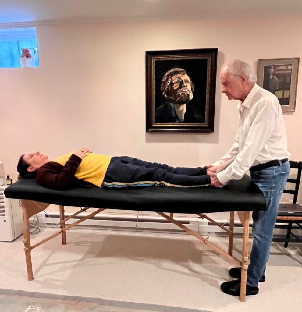 Tommy Thompson gently holding a trainee’s feet during Alexander Technique Class 58, demonstrating embodied stillness