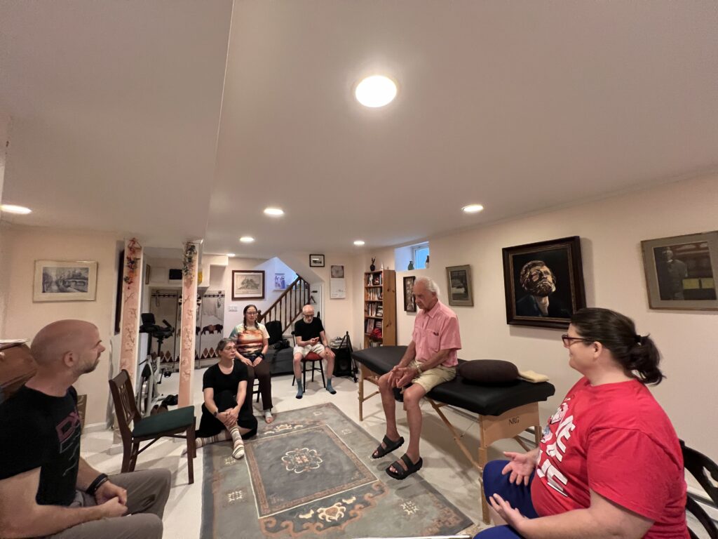 Wide view of Alexander Technique Class 075 with Tommy Thompson guiding a group of trainees in a shared learning space